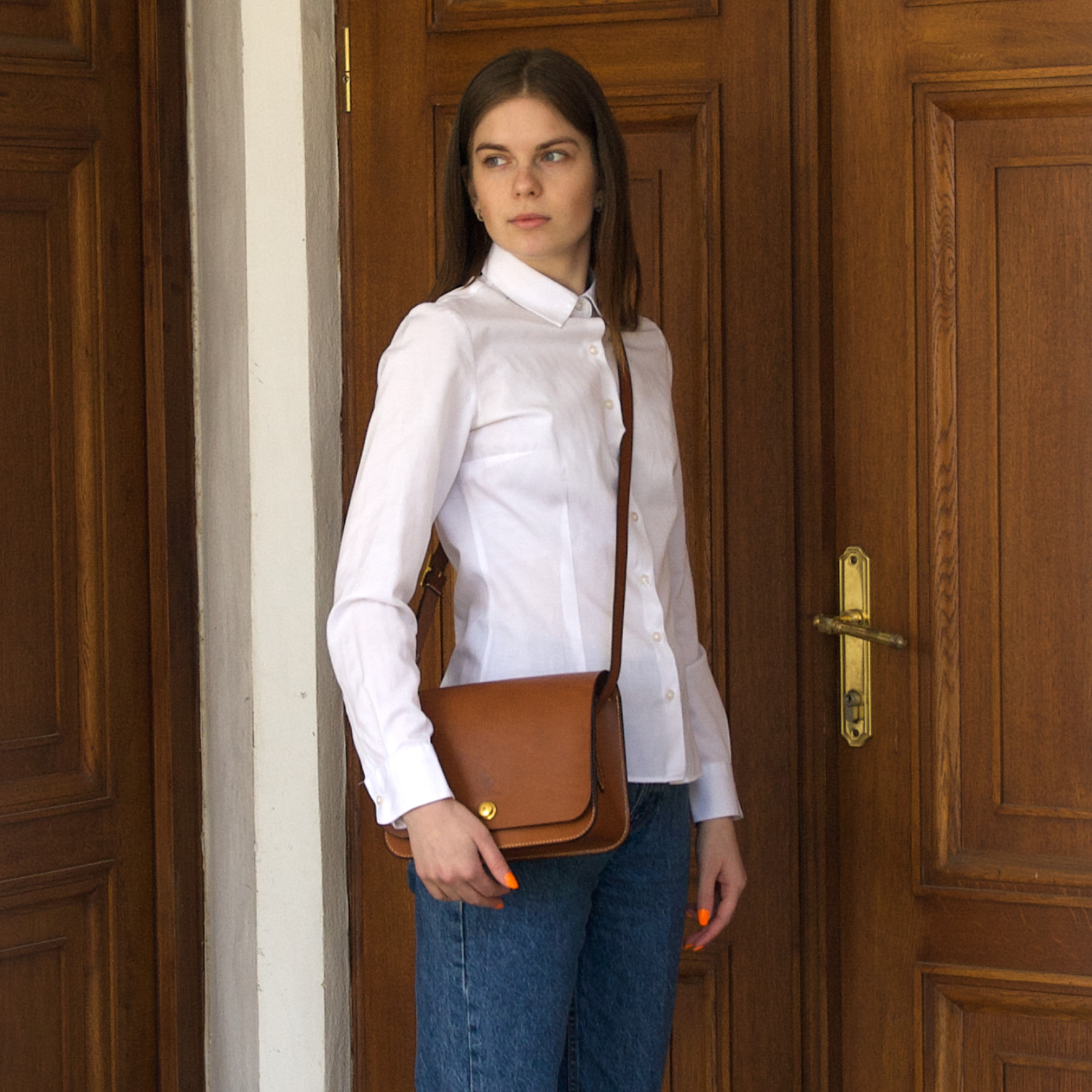 model carries leather crossbody handbag